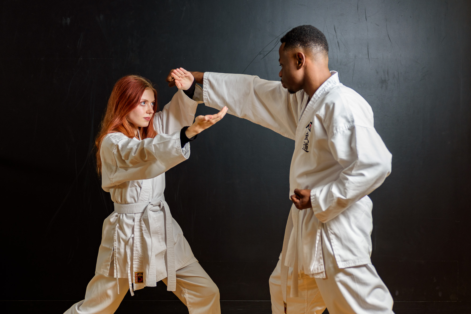 Two men on the mat practicing Karate in their white uniforms.